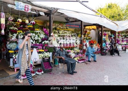 Una donna passeggia davanti a un negozio di fiori vicino al mercato del quartiere, islamabad, pakistan. Foto Stock