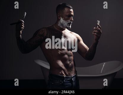 Uomo bearded che ottiene il taglio dei capelli dal parrucchiere al barbershop. Affilato. Crema per la rasatura in legno di sandalo. Balm su parti del corpo asciutte per idratare la pelle. Vecchio Foto Stock