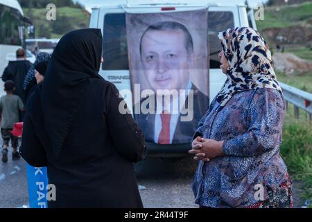 Due donne hanno visto in piedi davanti ad una bandiera con il ritratto del presidente Recep Tayyip Erdogan. Il presidente turco Recep Tayyip Erdogan, leader del Partito Giustizia e sviluppo (AKP), ha partecipato ad un raduno elettorale nel distretto di Nurdagi, nella provincia di Gaziantep. Il centro della città di Nurdagi è stato gravemente distrutto dal doppio terremoto del febbraio, che ha colpito 11 province con più di 50,000 morti in Turchia. Il rally è stato organizzato insieme ad una cerimonia per la consegna delle nuove case costruite per le persone colpite dal terremoto. Foto Stock