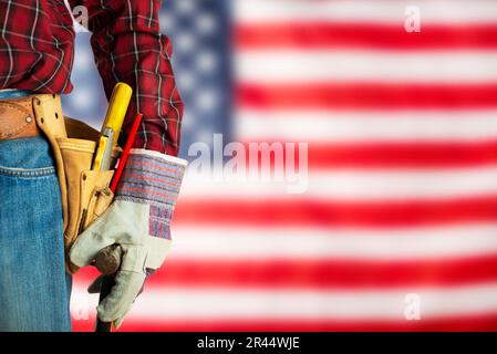 Lavoratore in guanti e cintura portautensili su di noi bandiera sfondo Labor Day mockup Foto Stock