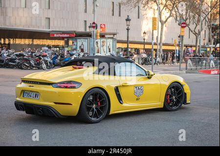 Vista posteriore di una vettura sportiva di lusso nelle strade di Barcellona, è una Porsche 718 Spyder gialla con un adesivo Tag Heuer 007 sulla porta Foto Stock