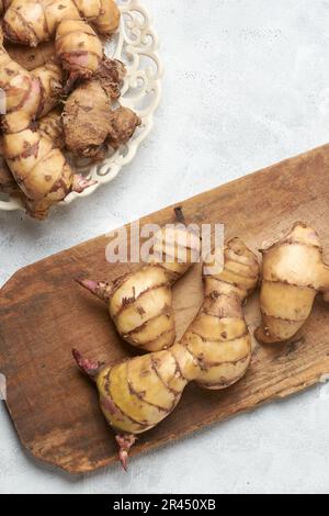 mucchio di razomi o tuberi della pianta di canna o del colpo indiano, indica di canna, yam valutato medicinale nativo alle regioni tropicali e subtropicali messe su legno Foto Stock