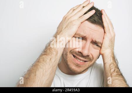 Bell'uomo è molto turbato, tiene le mani sulla testa Foto Stock