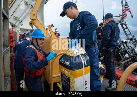 Il marinaio Kaige Caswell aiuta a scaricare e impilare balle di marijuana recuperate dall'Oceano Pacifico orientale 7 marzo 2023. STATI UNITI I membri della Guardia di costa Cutter Active (WMEC 618) hanno recuperato oltre 100 balle di marijuana scaricate a bordo da sospettati trafficanti di droga vicino a Golfito, Costa Rica. Foto Stock