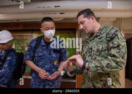 230320-N-RC359-1148 YOKOSUKA, Giappone (20 marzo 2023) Capo programma religioso Specialista Angelo Martinez, da Fajardo, Porto Rico, regali souvenir della Marina a un marinaio della forza di autodifesa marittima giapponese nel caos Chiefs a bordo degli Stati Uniti L’unica portaerei della Marina schierata a termine, la USS Ronald Reagan (CVN 76), durante un tour navale mentre il comandante in porto, Fleet Activities Yokosuka, marzo 20. Ronald Reagan, il fiore all'occhiello del Carrier Strike Group 5, fornisce una forza pronta per il combattimento che protegge e difende gli Stati Uniti, e sostiene le alleanze, le partnership e gli interessi marittimi collettivi nell'interno Foto Stock