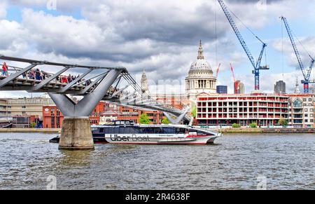 Londra il Millennium passerella sul fiume Tamigi che conduce verso la Cattedrale di St Pauls e Uber barca che passa sotto il ponte Foto Stock