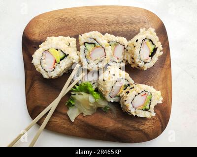 Una tavola di legno con sushi roll Foto Stock