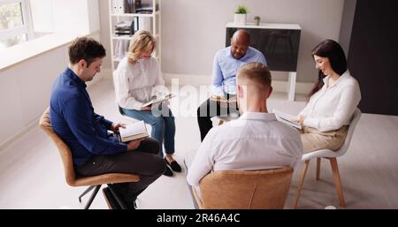 Gruppo di persone seduti su una sedia in cerchio lettura Bibbie Foto Stock