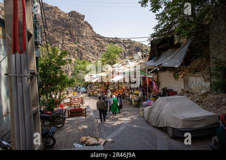 La gente che cammina lungo la stretta strada urbana con negozi in Iran Foto Stock
