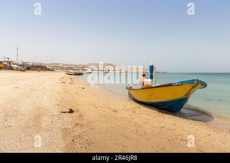 Una barca gialla sulla costa di una spiaggia sull'Isola di Hengam, una destinazione popolare tra i turisti nazionali in Iran. Foto Stock