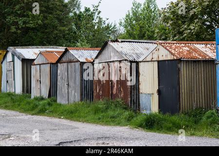 Vecchie capannoni di stagno arrugginito su terra di spreco Foto Stock