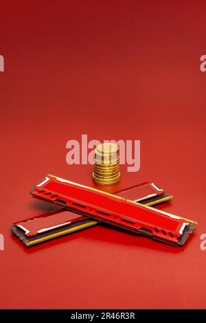 Alcuni moduli di memoria a DDR4 RAM incrociati con dissipatori metallici rossi su una superficie liscia rossa e con alcuni euro in monete dietro Foto Stock