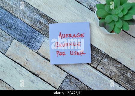 Concetto di ricavo medio per utente scrivere su note appiccicose isolate su tavola di legno. Foto Stock