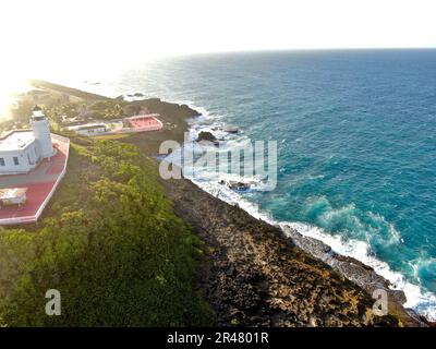 Un idilliaco scenario costiero caratterizzato da una pittoresca casa bianca situata vicino al litorale, con una spiaggia dorata Foto Stock