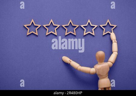 Banner di feedback o valutazione. Uomini di legno appende cinque stelle sul muro. Il concetto di customer experience di valutazione dei migliori servizi aziendali eccellenti. Foto Stock