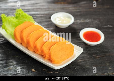 Tamagoyaki, omeletto di uovo laminato giapponese su tavola di legno. Servito con salsa e maionese Foto Stock