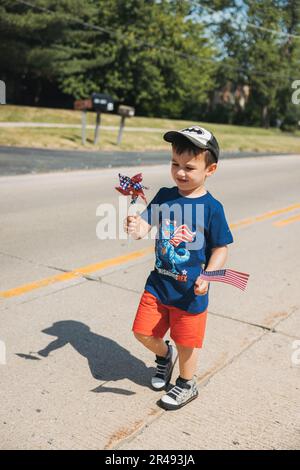 Un giovane, caucasico in un berretto, con una bandiera americana, che cammina per strada Foto Stock