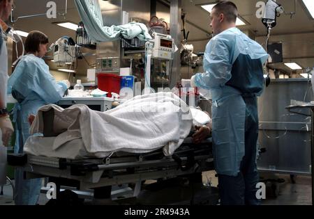 IL personale medico della Marina DEGLI STATI UNITI lavora diligentemente su un US ferito Marine Inside the Casualty Receiving Area (CASREC) a bordo della nave militare USNS Comfort (T-AH 20) Foto Stock