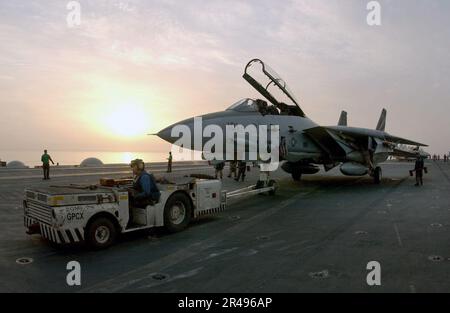 US Navy un aereo da combattimento F-14A Tomcat viene portato in posizione sul ponte di volo da un trattore a bordo della USS Kitty Hawk (CV 63) Foto Stock