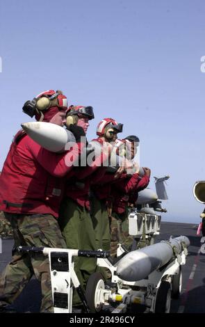 US Navy Aviation Ordnancemen solleva un missile Air-to-Air (AMRAAM) di gamma media e avanzata per attaccarlo a un F-A-18 Hornet a bordo di USS Nimitz (CVN 68) Foto Stock