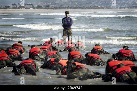 US Navy durante un'evoluzione del surf drill della settimana dell'Inferno, un istruttore di NAVY SEAL aiuta gli studenti della classe 245 Basic Underwater Demolition-SEAL (BUD-S) ad apprendere l'importanza dell'ascolto Foto Stock
