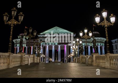 Statue che decorano il Ponte delle civiltà, di fronte al Museo Archeologico di Skopje, Macedonia settentrionale. Di notte con lampioni che illuminano il ponte. Foto Stock