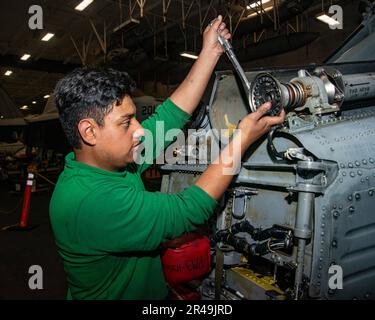 230405-N-NX635-1129 (5 aprile 2023) US Navy Aviation Machinist's Mate 3rd Class Anthony Avila, di Los Angeles, accoppia l'accoppiamento flessibile di un elicottero MH-60s Sea Hawk nella baia hangar a bordo della portaerei USS Nimitz (CVN 68). Il Nimitz Carrier Strike Group sta conducendo un esercizio marittimo bilaterale con la Marina della Repubblica di Corea nell'area operativa della flotta statunitense 7th. 7th Fleet è la flotta statunitense La più grande flotta di numeri della Marina distribuita in futuro, interagisce e opera regolarmente con alleati e partner per preservare una regione indomorosa e libera. Foto Stock