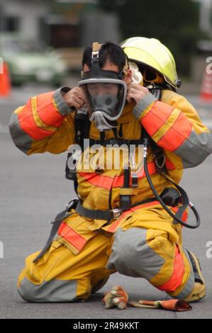 US Navy Un pompiere assegnato al Comandante USA Naval Forces Japan (CNFJ) Vigili del fuoco regionali Dons equipaggiamento di protezione Foto Stock
