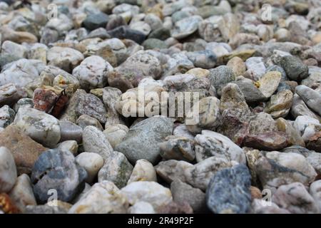 Un primo piano ad alta risoluzione di una varietà di pietre e ciottoli lisci in un ambiente da spiaggia, caratterizzato da colori e texture naturali e terreni Foto Stock