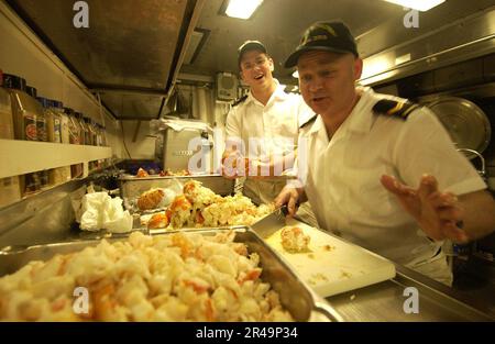 I marinai DELLA US Navy a bordo della Canadian Navy Halifax-class pattuglia fregata HMCS Toronto (FFH 333), preparano coda di aragosta appena cucinata per pranzo Foto Stock