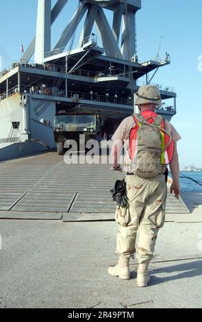 US NAVY A U.S. Marine attende un camion tattico M-977 Heavy Expanded Mobility (HEMTT) per scendere dalla rampa del comando militare Sealift (MSC) nave veloce USNS Bellatrix (T-AKR 288) Foto Stock