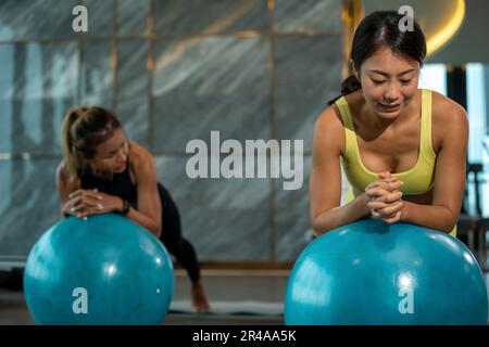 Umorismo nello sport Ball Yoga. Donna asiatica grassa con la sua formazione di insegnante di Yoga Instrutor in ginnastica con palla fitness. Donna asiatica sportiva che fa esercizio Foto Stock