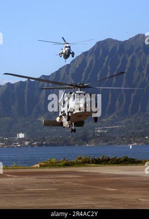 US Navy un elicottero SH-60B Seahawk assegnato ai Easy Riders of Helicopter Anti-sottomarino Squadron Light Three Seven (HSL-37), arriva davanti a un elicottero UH-3H Sea King Foto Stock