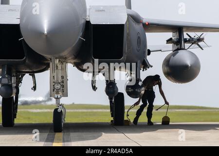 NEGLI STATI UNITI Il manutentore dell'aeronautica della 336th Aircraft Maintenance Unit tira i cunei da una F-15E Strike Eagle alla base aerea di Kadena, Giappone, 8 aprile 2023. The Strike Eagle è un combattente a due ruoli con capacità aria-aria e aria-terra. Un'ampia gamma di sistemi di elettronica e avionica offre al F-15E la capacità di combattere a bassa altitudine, di giorno o di notte e in qualsiasi condizione climatica. Foto Stock