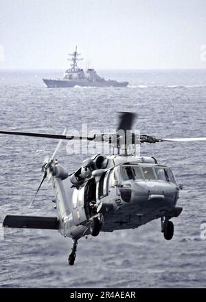 US Navy un MH-60s Knighthawk assegnato a Helicopter Combat Support Squadron Five (HC-5), conduce un rifornimento in corso (UNREP) con il cacciatorpediniere missilistico guidato USS Benfold (DDG 65) e USS Abraham Linco Foto Stock