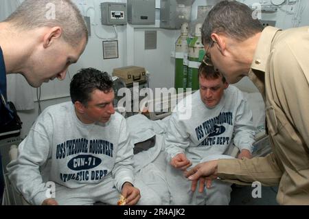 US Navy John Raye e Corey Glynn di Ottawa, Canada, ricevere assistenza medica da CMdR. Edward Jorgensen, il medico ufficiale a bordo della portaerei di classe Nimitz USS Theodore Roosevelt (CVN 71) Foto Stock