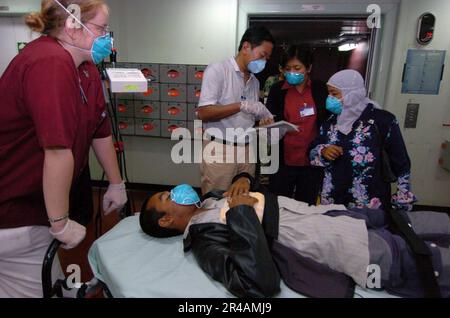 US Navy un interprete indonesiano assiste il personale medico militare mentre un nuovo paziente viene registrato a bordo della nave ospedaliera USNS Mercy (T-AH 19) Foto Stock