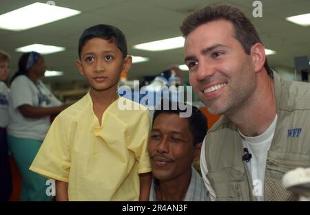 US Navy New York Giants quarterback Kurt Warner posa per una foto con un ragazzo indonesiano e un membro della sua famiglia a bordo del militare Sealift Command (MSC) nave ospedale USNS Mercy (T-AH 19) Foto Stock