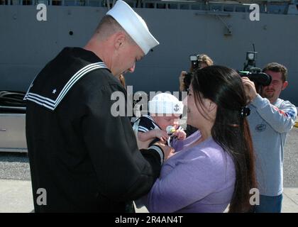 US Navy Fire Controlman 1st Class abbraccia il suo nuovo figlio con moglie per la prima volta dopo il ritorno dal dispiegamento a bordo del cacciatorpediniere missilistico guidato USS The Sullivans (DDG 68) Foto Stock