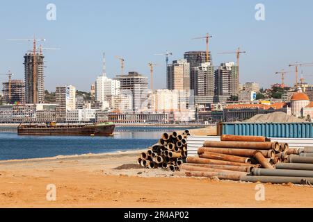 Vista della città costiera di Luanda in fase di ricostruzione, sul bordo della baia. Cantieri edili, pali di tubi.. Foto Stock