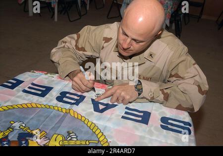 US Navy Lt. CMdR. Il Navy Chaplain assegnato al Naval Mobile Construction battaglione due tre (NMCB-23), firma una bandiera Seabee. Foto Stock
