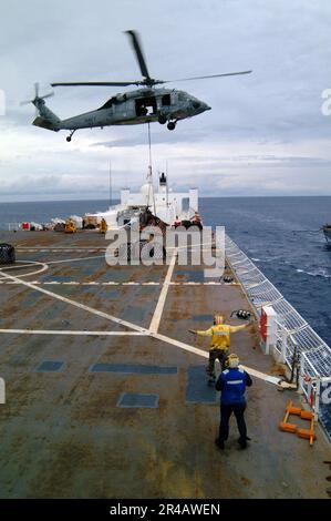 US Navy A Landing Signal arlisted Sailor guida un elicottero MH-60s Seahawk, assegnato a Helicopter Combat Support Squadron Five (HC-5), durante un reintegro verticale. Foto Stock