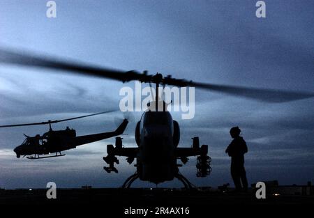 US Navy un AH-1W Super Cobra si mette sul ponte a bordo del molo di trasporto anfibio USS Duluth (LPD 6) mentre un UH-1N Huey decolta durante le operazioni di volo di routine nello stretto di Hormuz. Foto Stock