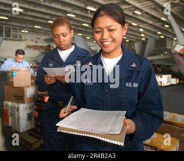 IL magazzino US Navy 3rd Class verifica le attrezzature e le forniture per l'aviazione portate a bordo dai fornitori di supporto logistico del vettore Squadron Three Zero (VRC-30), nella baia hangar a bordo di USS. Foto Stock