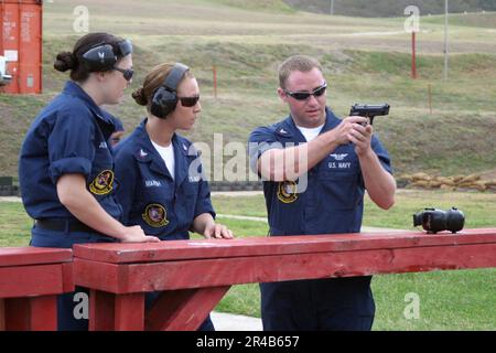 US Navy Aviation Ordnanceman 3rd Classe destra, istruisce Aviation Electrician sulla tecnica di sparo adeguata di un 9. Foto Stock