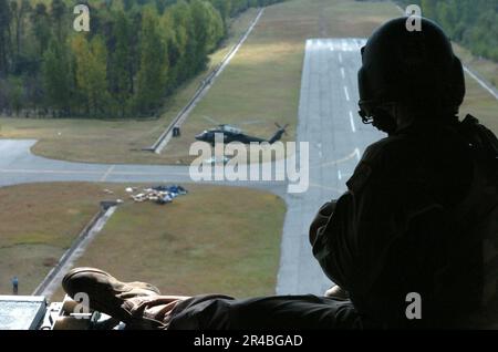 US NAVY A U.S. Il membro dell'equipaggio dell'esercito siede sulla rampa di un elicottero CH-47 Chinook mentre un elicottero UH-60 Blackhawk decollerà sotto dopo aver lasciato gli aiuti di emergenza al remoto villaggio pakistano di Rawalakot. Foto Stock