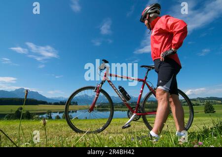 Ciclista, Forggensee, Allgaeu, Baviera, Germania Foto Stock