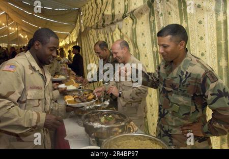 US Navy U.S.A. Mike Lefever, centro, serve la cena del giorno del Ringraziamento lungo il lato 212th Mobile Army Surgical Hospital (MASH) Commander col. E Command Sgt. Major. Foto Stock