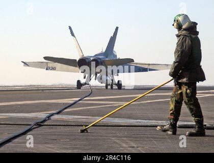 US Navy Airman guida un filo di arresto retrattile dopo che un F-A-18C Hornet atterra a bordo della portaerei di classe Nimitz USS George Washington (CVN 73). Foto Stock