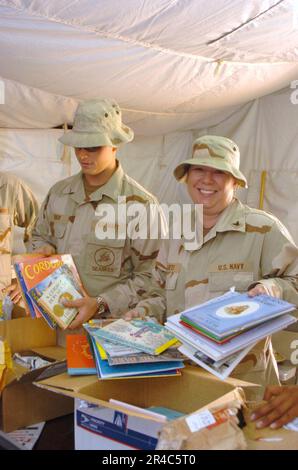 US Navy Construction Mechanic Constructionman sinistra, e culinary Specialist 3rd Classe aiutare a disimballare le centinaia di libri donati. Foto Stock